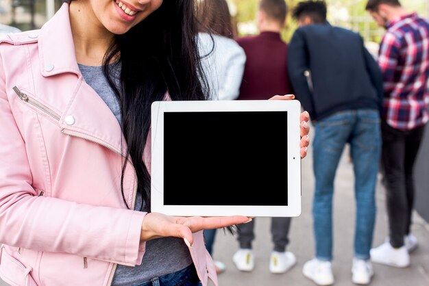 Primer plano de una mujer sonriente sosteniendo tableta digital con pantalla negra en blanco