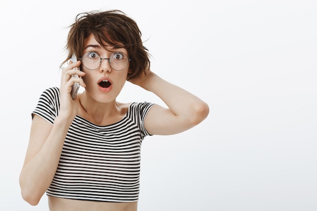 Primer plano de mujer sorprendida jadeante aprender secreto mientras habla por teléfono, mirando emboscado