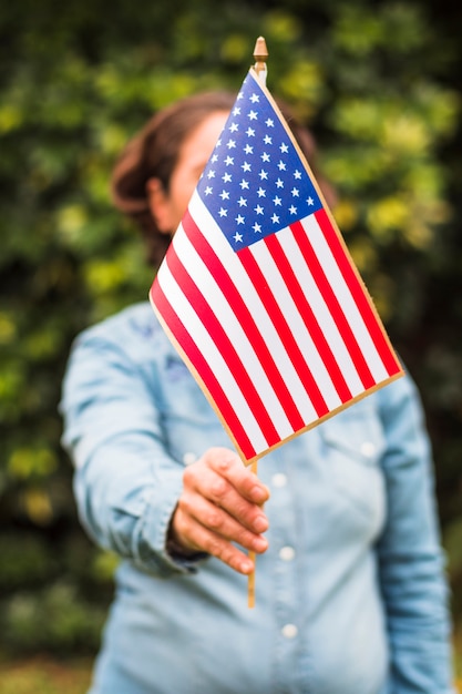 Primer plano de una mujer sosteniendo la bandera estadounidense de Estados Unidos delante de su cara