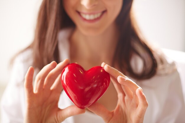 Primer plano de una mujer sosteniendo un corazón brillante