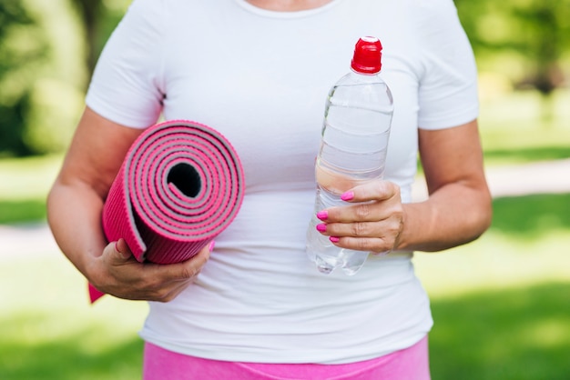 Foto gratuita primer plano mujer sosteniendo estera de yoga