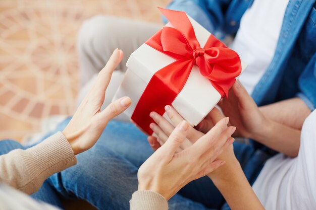 Primer plano de mujer sosteniendo un regalo con un lazo rojo