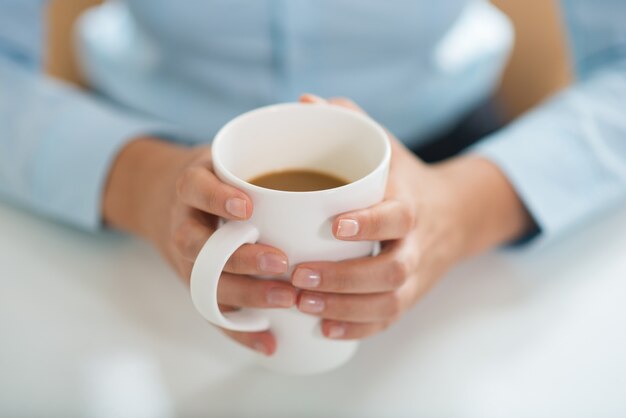 Primer plano de mujer sosteniendo una taza y tomando café