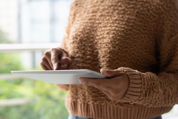 Primer plano de mujer en suéter caliente usando tableta en balcón