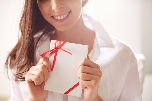 Primer plano de mujer sujetando una tarjeta con cinta roja