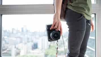 Foto gratuita primer plano, de, un, mujer, tenencia, cámara, posición, cerca de ventana