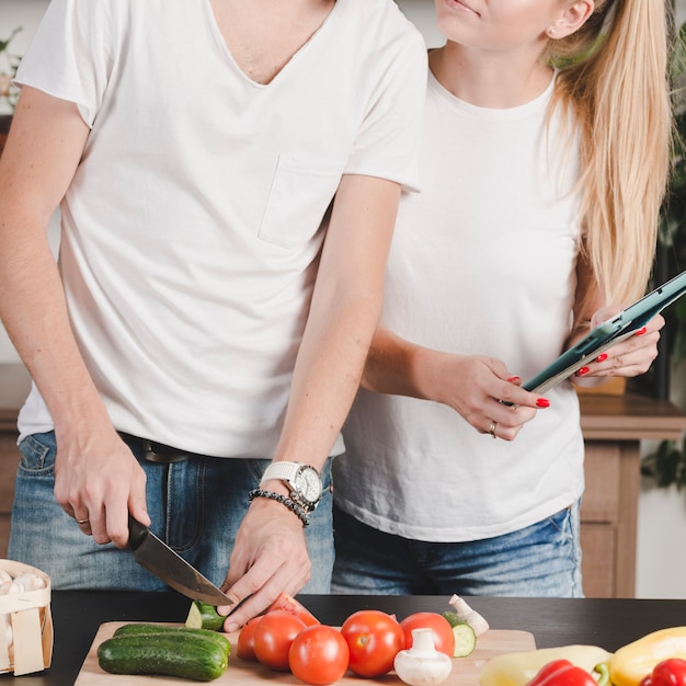 Primer plano, de, mujer, tenencia, computadora portátil, y, ella, novio, corte, vegetales