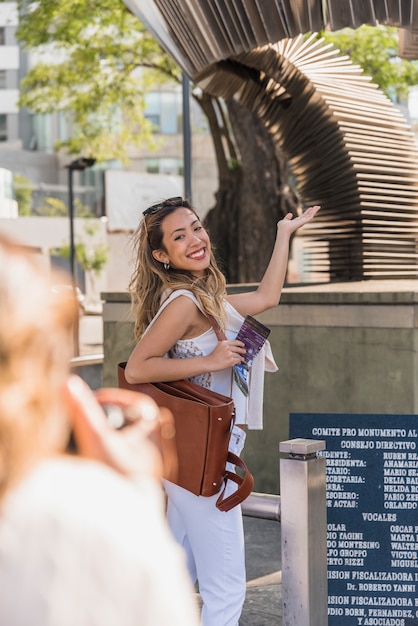 Primer plano de mujer tomando una fotografía de su amiga posando en el exterior