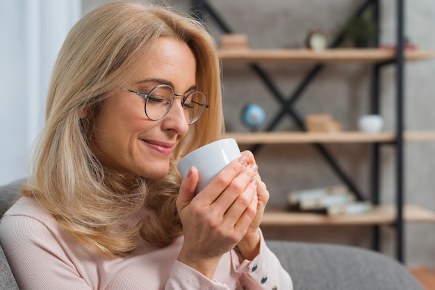 Primer plano de una mujer tomando olor a café con los ojos cerrados