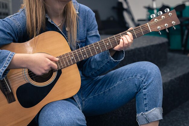 Primer plano una mujer en un traje de mezclilla toca la guitarra