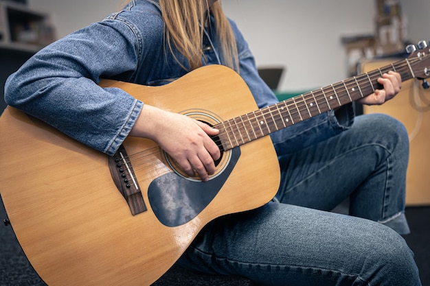 Primer plano una mujer en un traje de mezclilla toca la guitarra