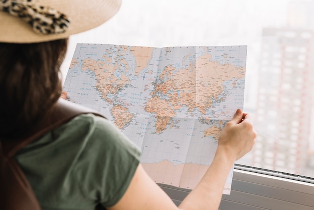 Primer plano de una mujer turista leyendo el mapa cerca de la ventana