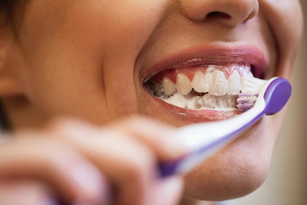 Primer plano de una mujer usando un cepillo de dientes mientras se limpia los dientes