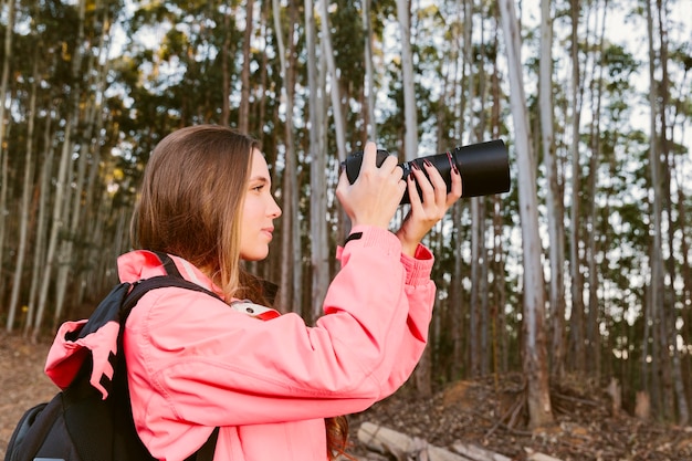 Primer plano de mujer viajero fotografiando en el bosque