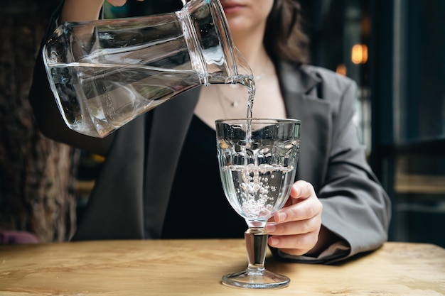 Foto gratuita primer plano una mujer vierte agua en un vaso en un café