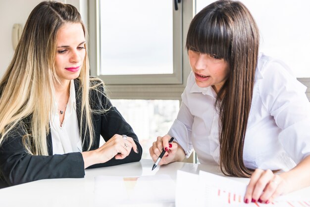 Primer plano de mujeres empresarias analizando el informe de negocios en la oficina