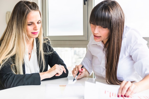 Primer plano de mujeres empresarias analizando el informe de negocios en la oficina