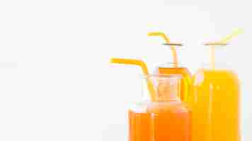 Foto gratuita primer plano de una naranja y botellas de jugo de mango con pajitas aisladas sobre fondo blanco