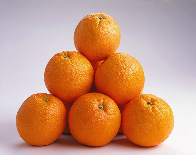 Primer plano de naranjas una encima de la otra sobre una superficie blanca, ideal para un fondo