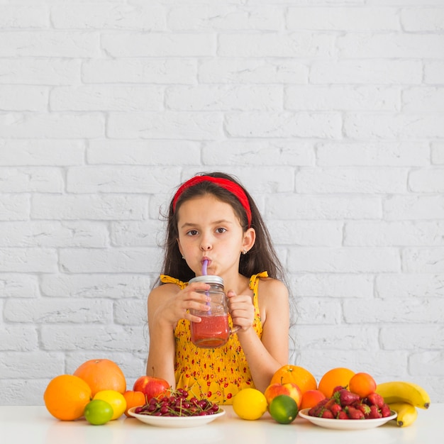 Primer plano de una niña bebiendo batidos de fresa