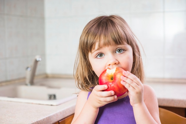 Primer plano de una niña comiendo manzana roja saludable