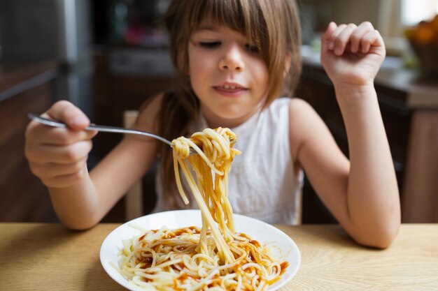 Primer plano niña comiendo plato de pasta