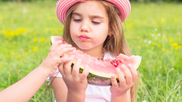 Primer plano de una niña comiendo sandía en el parque