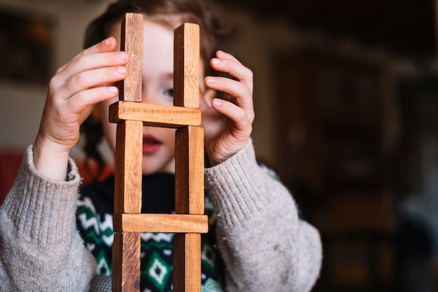 Primer plano de una niña equilibrando bloques de madera apilados