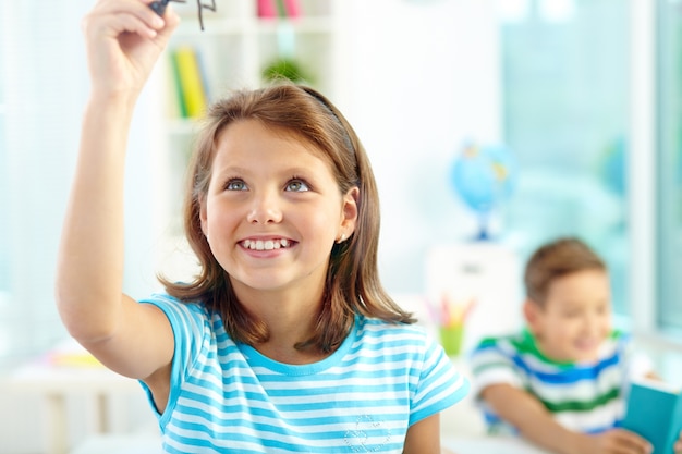 Primer plano de niña escribiendo en la pizarra