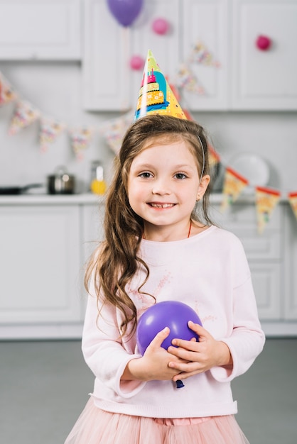 Foto gratuita primer plano de una niña feliz con globo morado