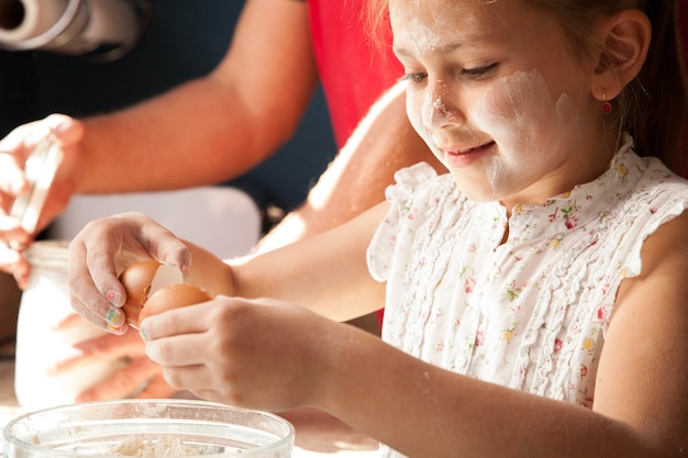 Primer plano de niña feliz rompiendo un huevo