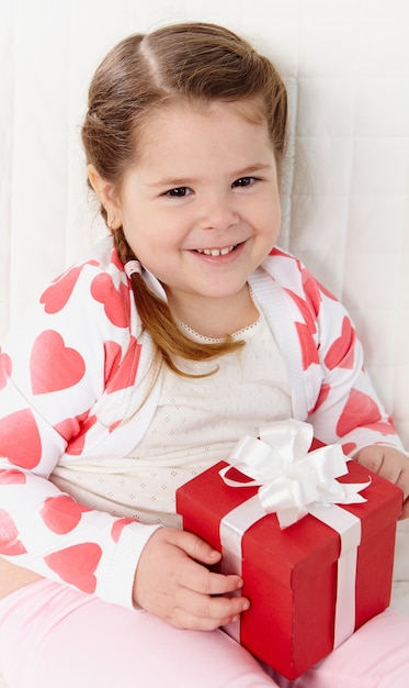 Primer plano de una niña linda con un regalo rojo