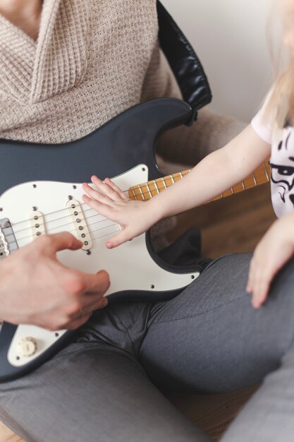 Primer plano de niña con una mano en la guitarra de su padre