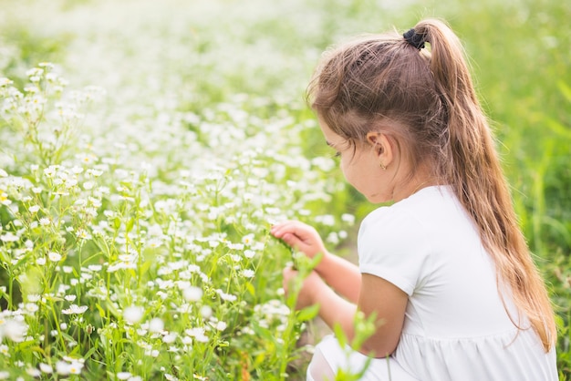 Foto gratuita primer plano de una niña mirando flores blancas salvajes