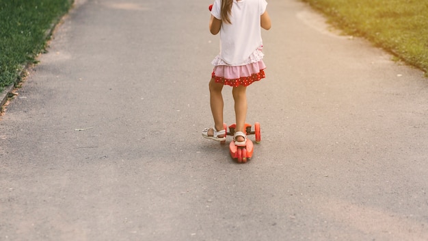 Foto gratuita primer plano de una niña montando scooter en la calle