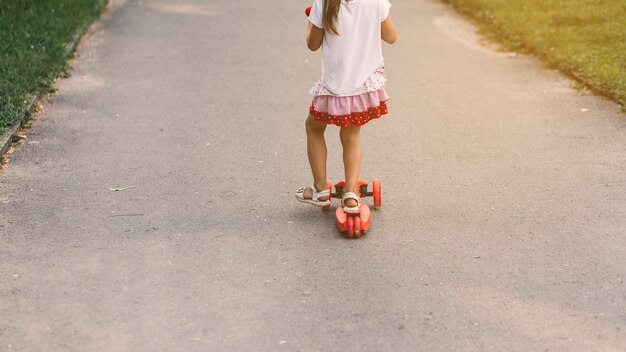 Primer plano de una niña montando scooter en la calle