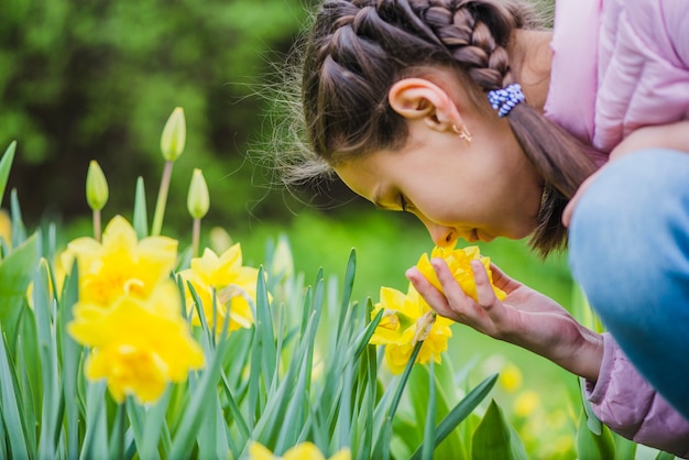 Foto gratuita primer plano de niña oliendo una flor