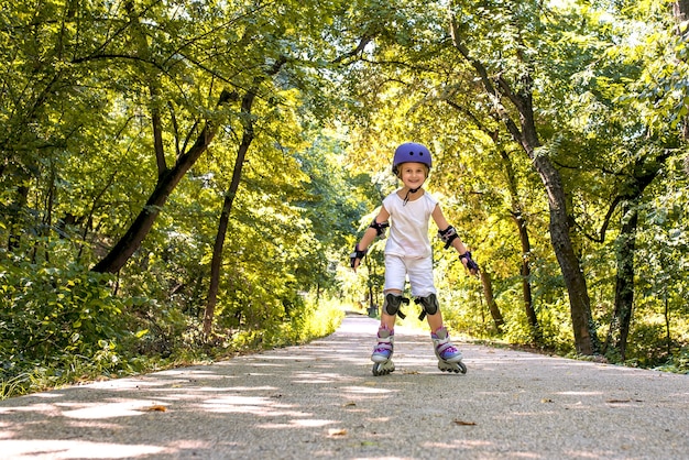 Primer plano de una niña de patinaje sobre ruedas en el parque rodeado de árboles