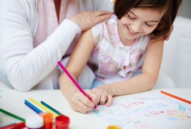 Primer plano de niña pequeña dibujando con su madre