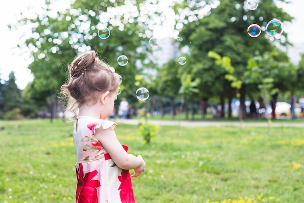 Primer plano de niña de pie en el parque con burbujas