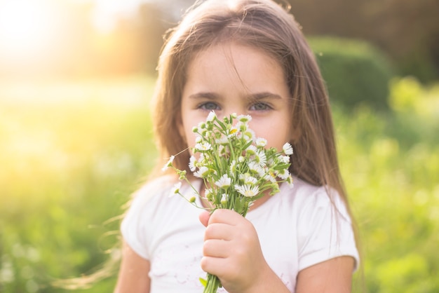 Primer plano de una niña que huele a flores blancas