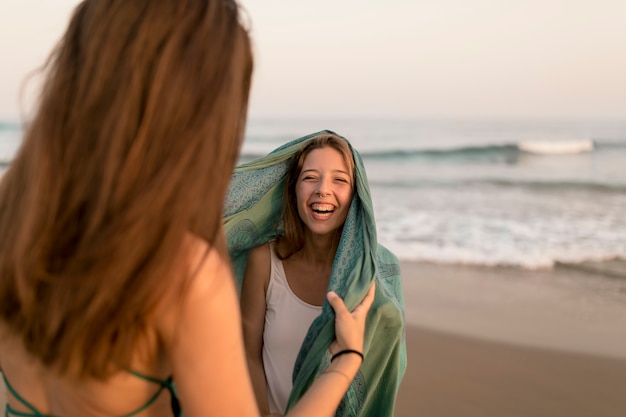 Primer plano de niña riéndose con su amigo en la playa