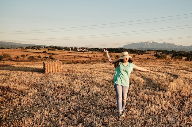 Primer plano de una niña con un sombrero redondo caminando en el campo