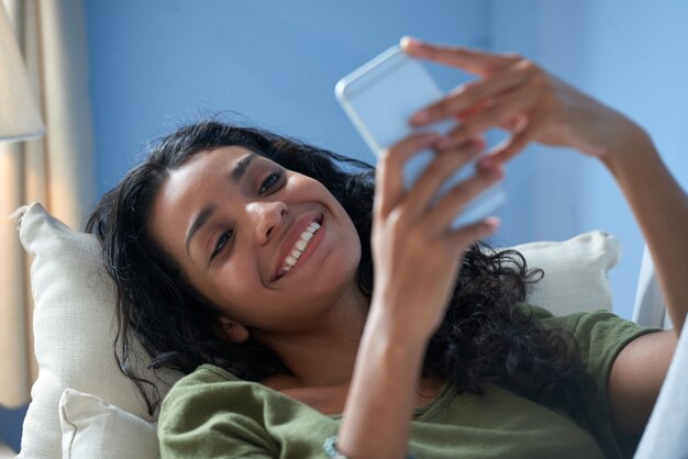 Primer plano de una niña sonriente enviando un mensaje de texto a su novio