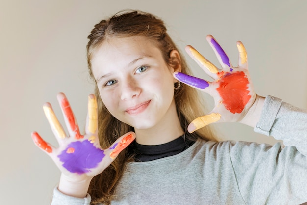 Primer plano de una niña sonriente con las manos pintadas