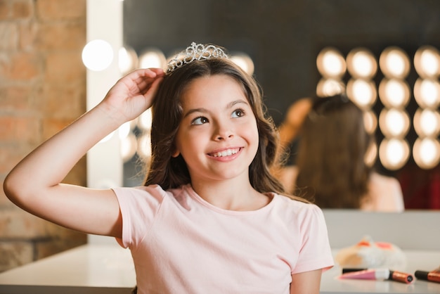 Primer plano de niña sonriente vistiendo corona soñando despierto