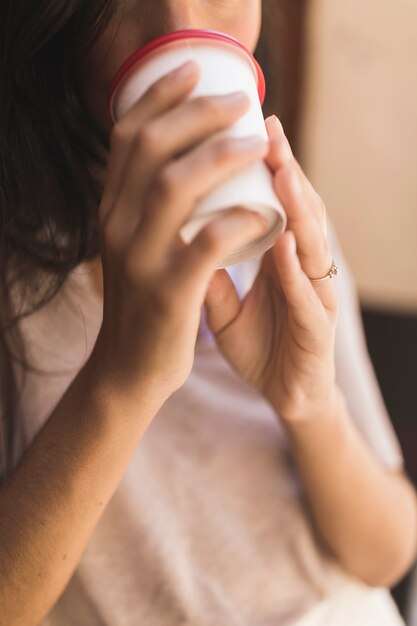 Primer plano de una niña tomando café de la taza de café para llevar