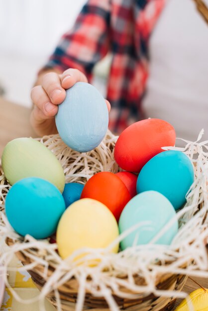 Primer plano de una niña tomando huevo de Pascua azul del nido