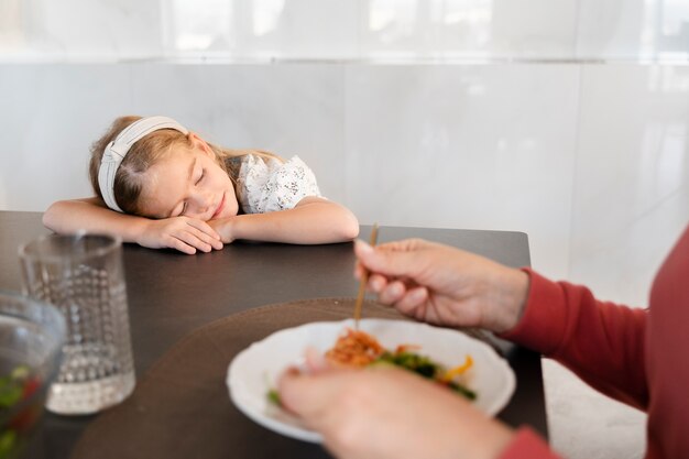 Primer plano de niña tomando una siesta después de la cena