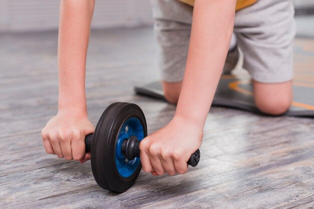 Foto gratuita primer plano de un niño arrodillado ejercicio con rodillo deslizante